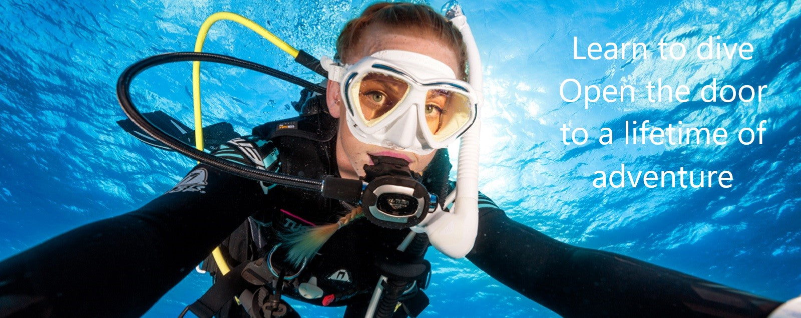A SCUBA diver with their arms wide open beckoning people to learn to scuba dive with them